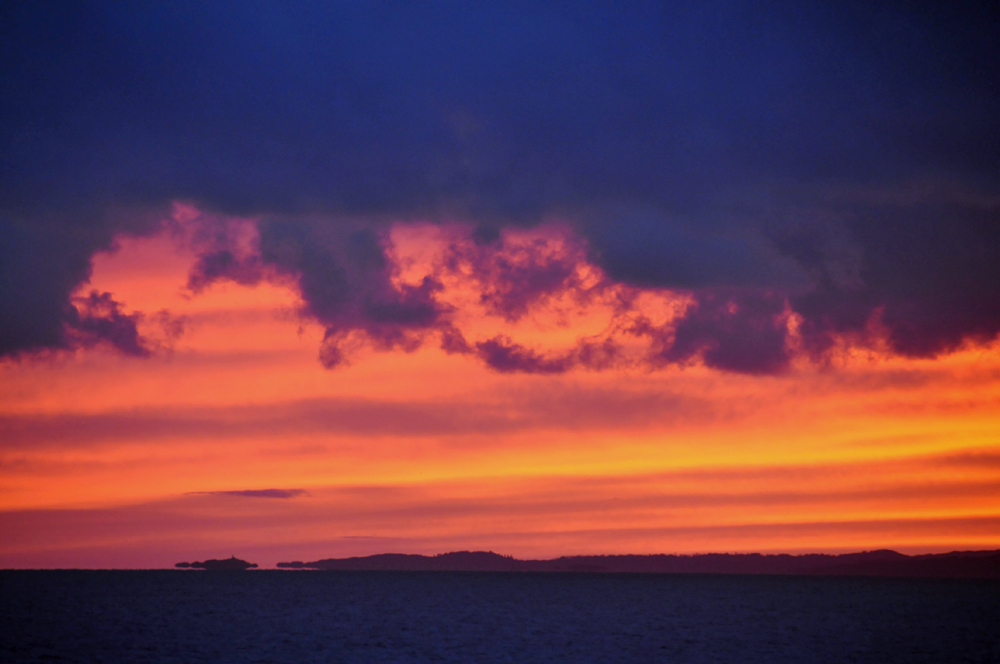 Picture of a colourful sunset with orange and red clouds under dark clouds