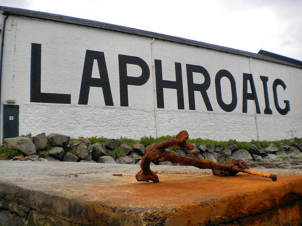 Picture of a rusty old anchor in front of the Laphroaig distillery warehouse