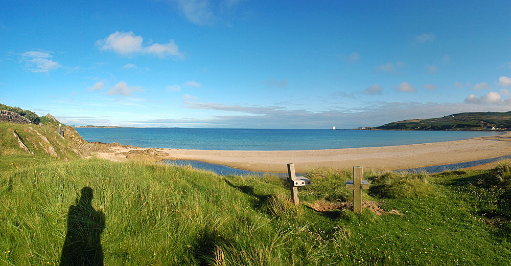 Picture of a panoramic view over a wide bay with a beach, lighthouse in the distance