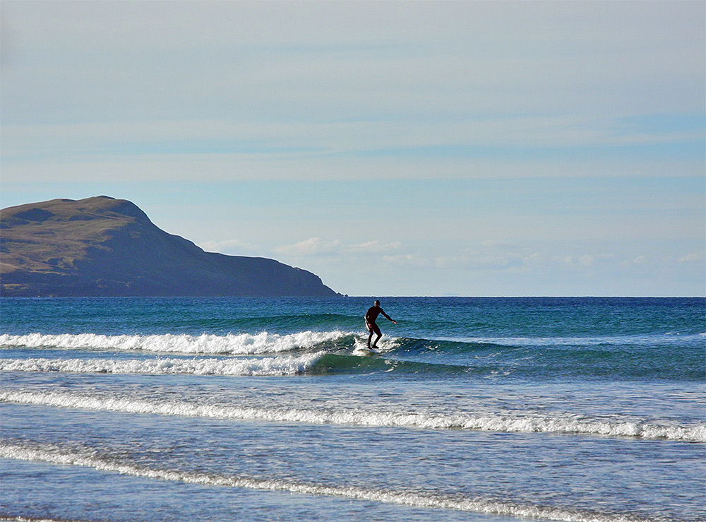 Picture of a surfer riding a wave on a bright sunny October day