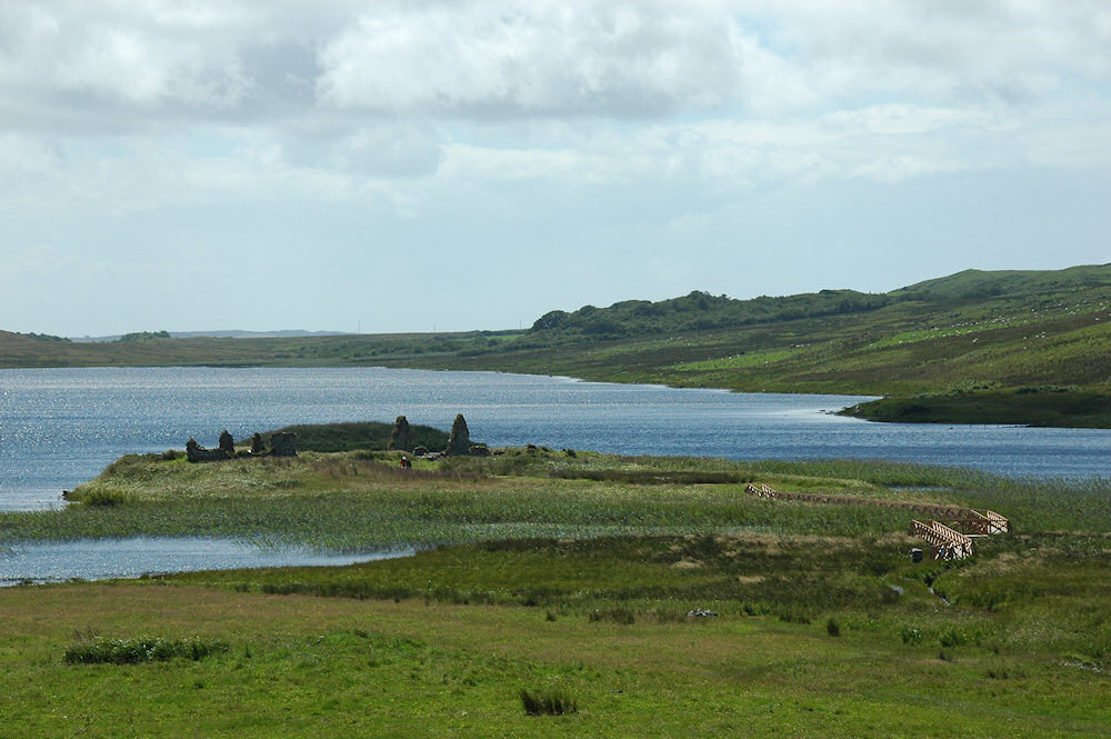 Picture of a loch with two small islands, a footbridge leading to the larger one