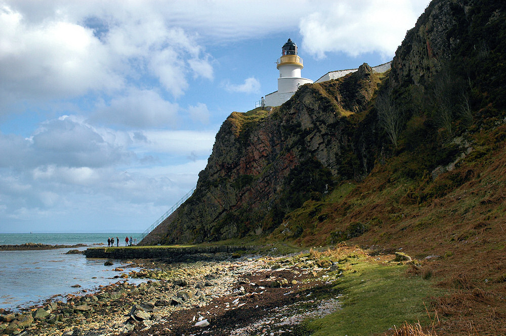 Picture of a view up to a lighthouse on the top of steep cliffs