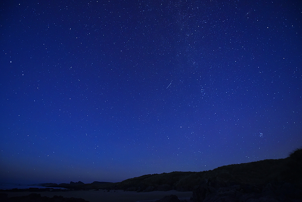Picture of a starry night sky over a bay with a sandy beach