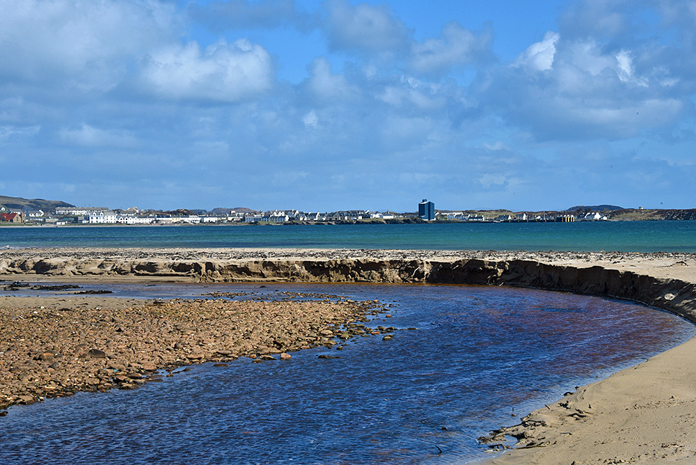 Picture of a harbour village seen from a beach across a bay