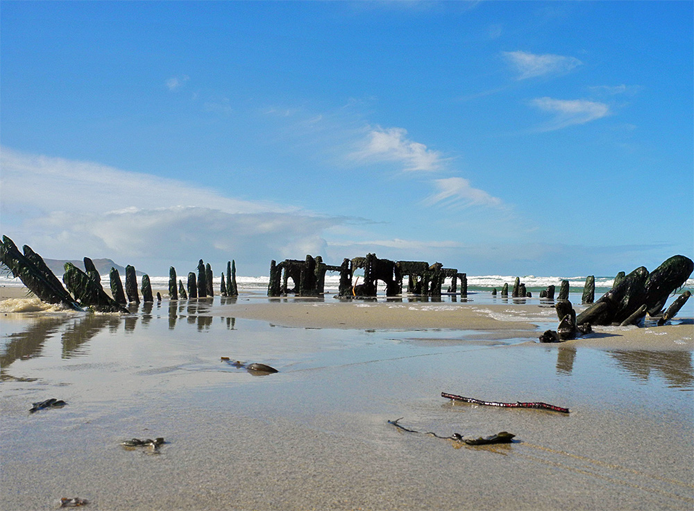 Picture of a view of wreck embedded in the sand of a beach from low down to the ground