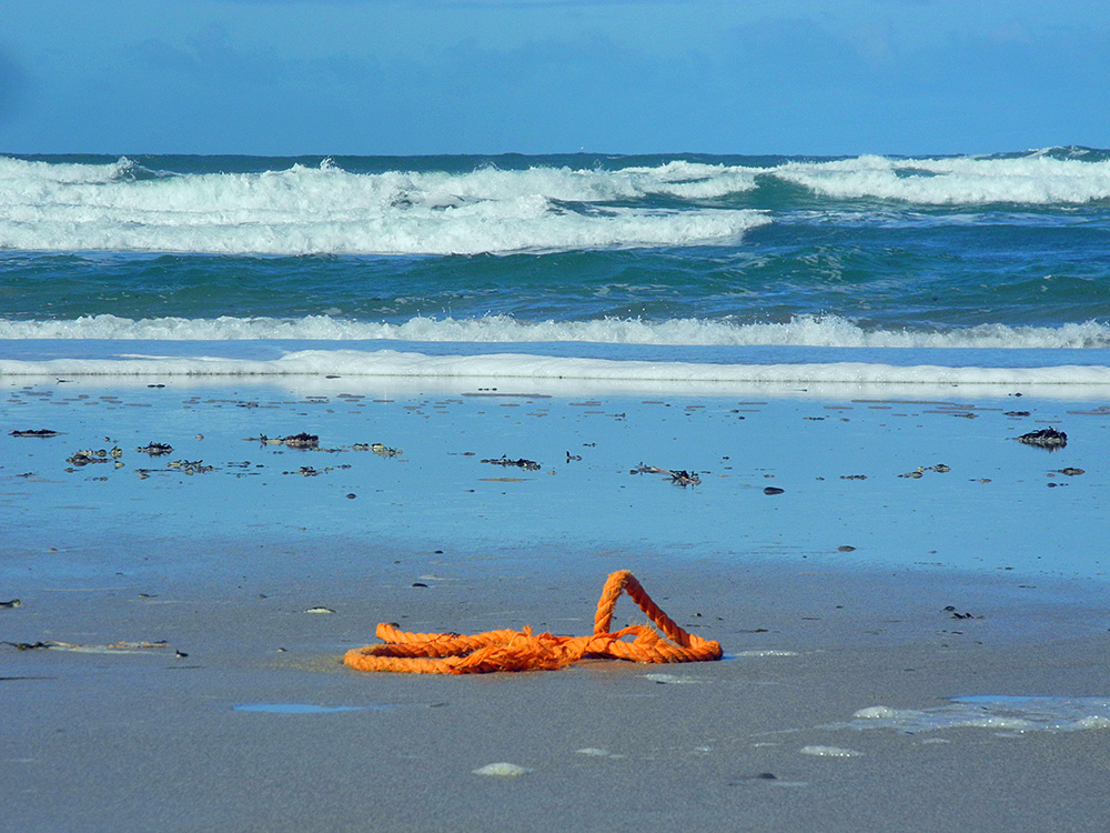 Picture of a short length of orange rope washed up on a beach