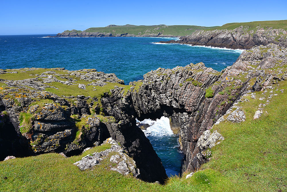 Picture of a natural arch with a bay in the background