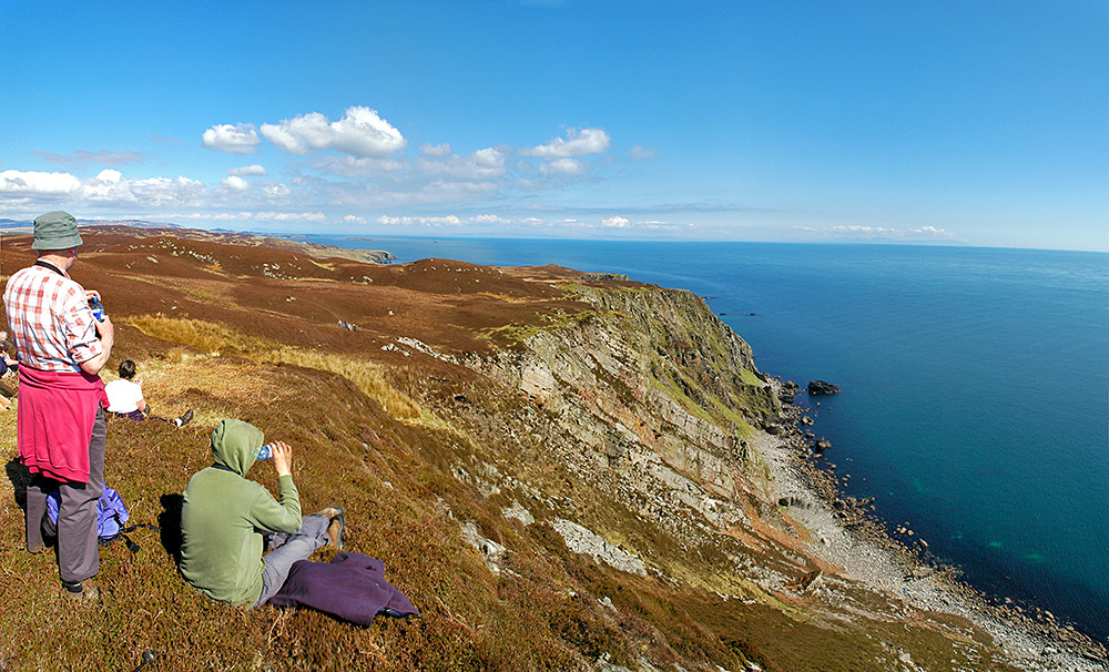 Picture of a group of walkers resting and enjoying the view from the top of cliffs high above the sea