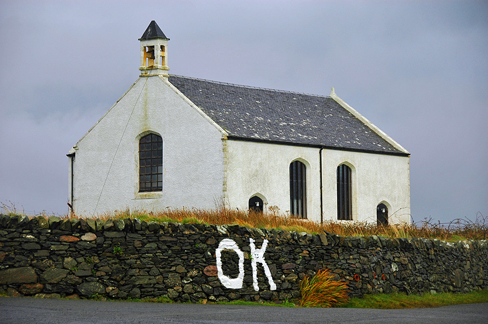 Picture of a small church behind a wall with "OK" painted on it