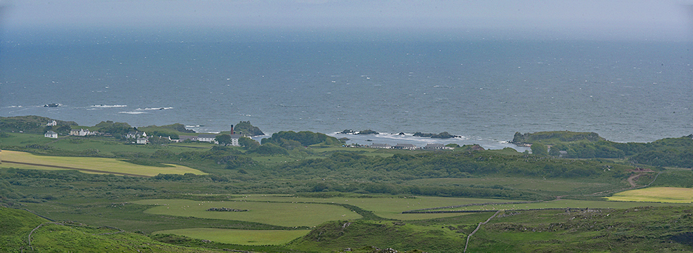 Panoramic picture of a small coastal village with a distillery and the ruin of a castle