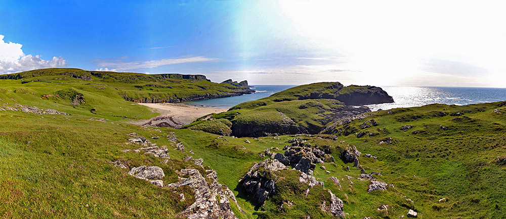 Panoramic picture of a coastal landscape with a small beach and various cliffs