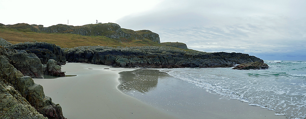 Panoramic picture of rocks at the end of a sandy beach