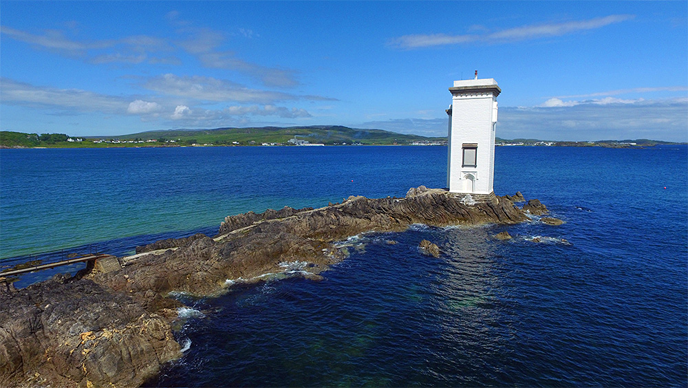 Picture of a square lighthouse out at the end of a rocky outcrop