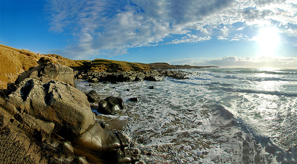 Panoramic picture of a bay with a beach at high tide on a spring evening