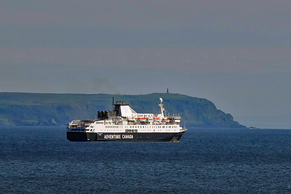 Picture of the cruise liner MS Ocean Endeavour passing a headland with a monument