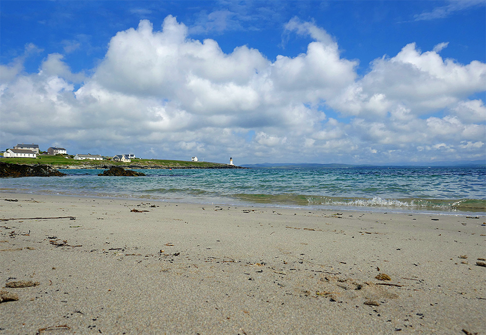 Picture of a small village beach, a lighthouse visible in the distance