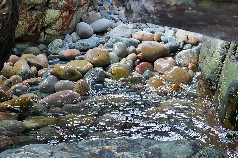 Picture of some round polished stones in a rocky opening on the shore