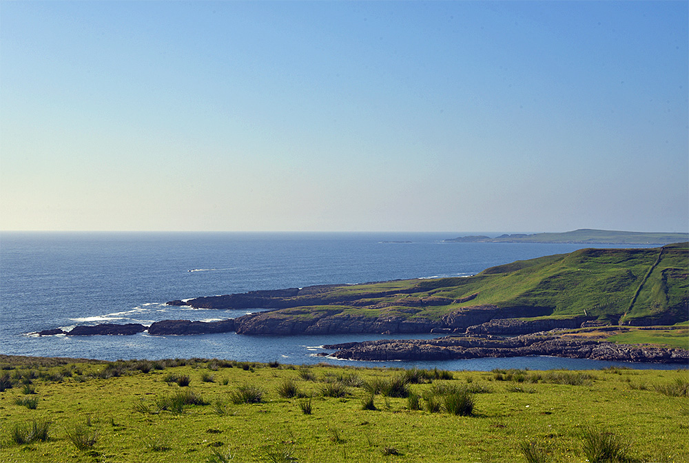Picture of a coastline seen from a hillside on a sunny day