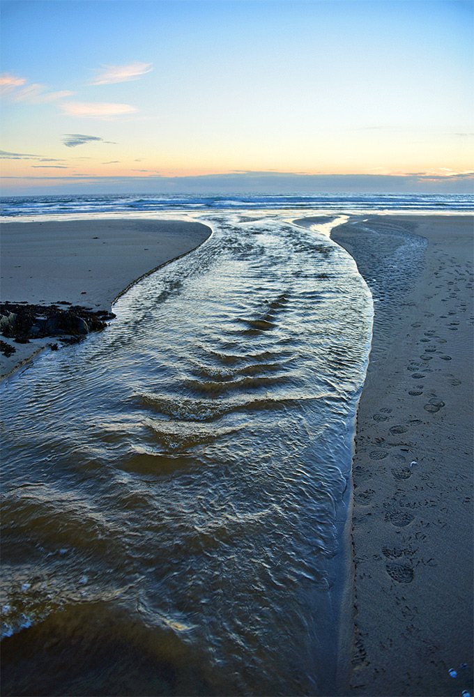 Picture of a stream flowing across a beach into the sea on a summer evening after sunset