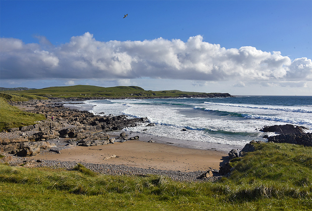 Picture of a bay with a beach and rocky shore, waves rolling in from the Atlantic
