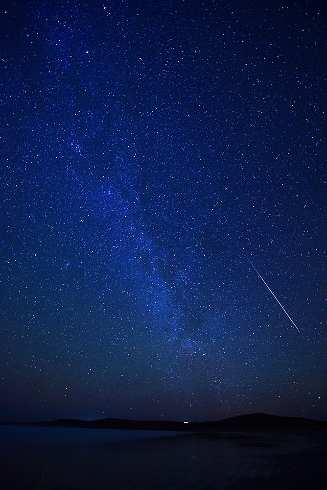 Picture of a starry sky with the Milky Way and a large meteor streaking across the view