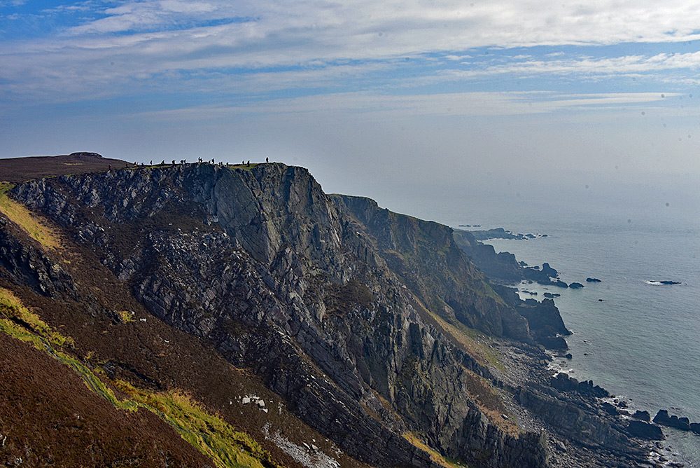 Picture of a group of walkers on the top of some high and steep cliffs above the sea