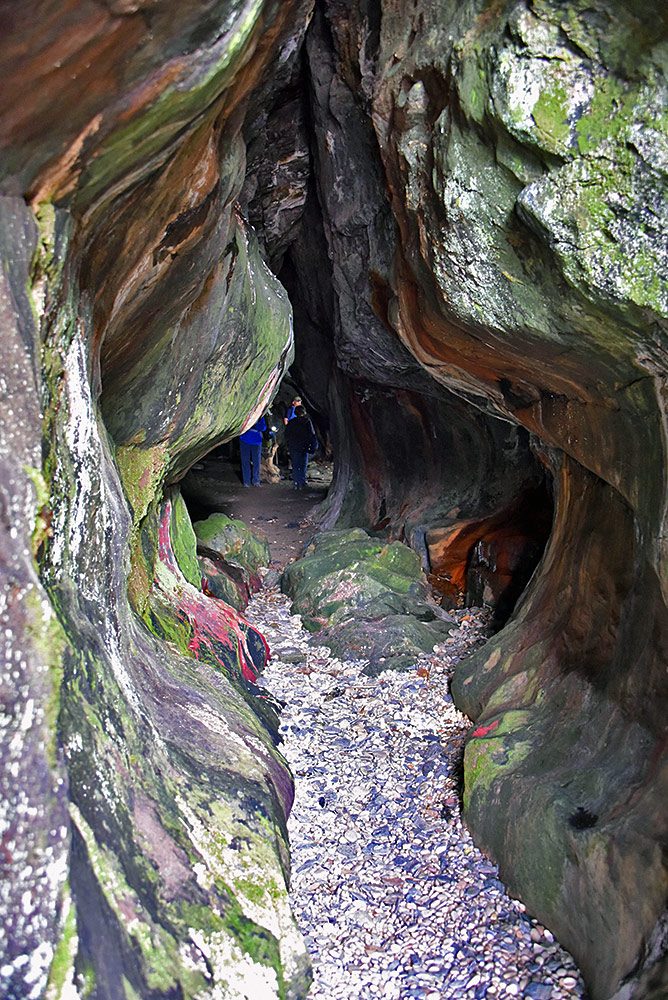 Picture of a view into a deep cave, people at the end of the cave
