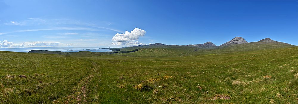 Panoramic picture from a hillpath out to sea and over some mountains