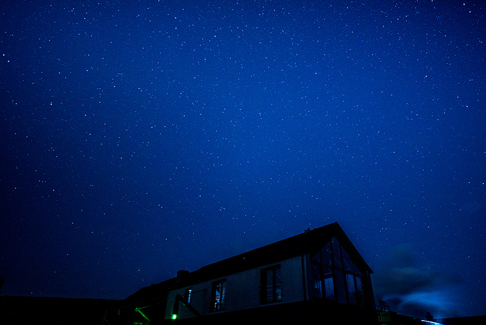 Picture of a starry night sky over a small farm distillery stillhouse