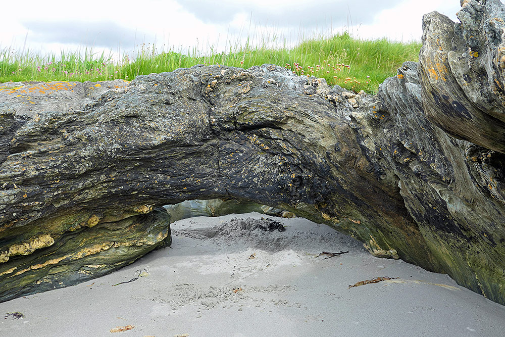 Picture of a very small natural arch over some sand