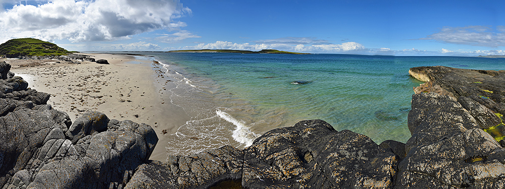 Panoramic picture of a view from a low cliff over a beach and a small offshore island