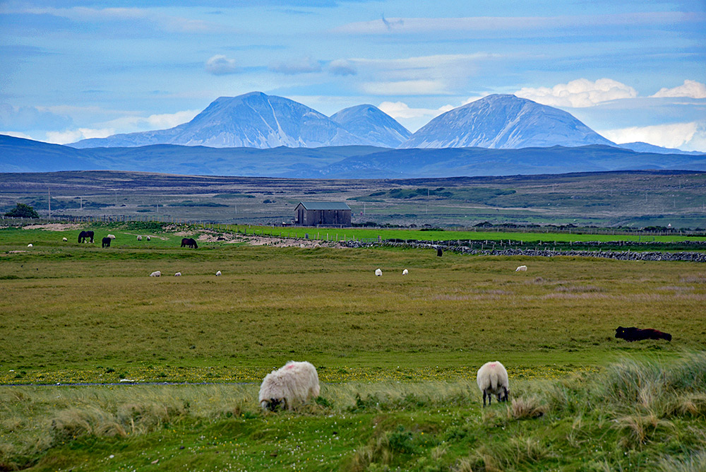 Picture of a landscape of farmland and moorland with three mountains in the background
