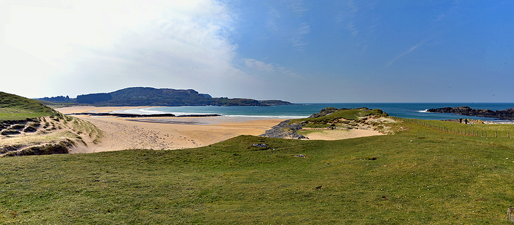 Panoramic picture of a bay with a wide sandy beach in the April sunshine