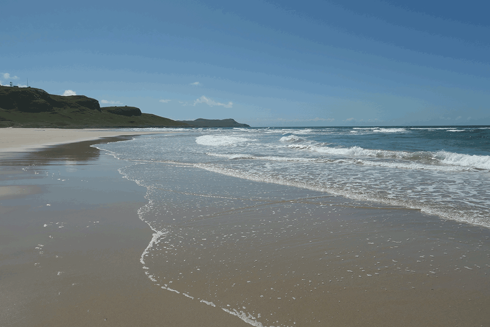 Animated picture of waves rolling on to a sandy beach on a sunny day