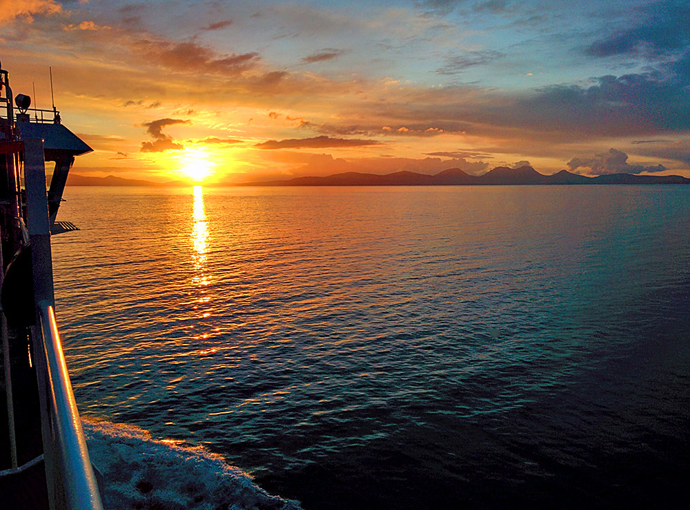 Picture of a sunset over two islands seen from a ferry