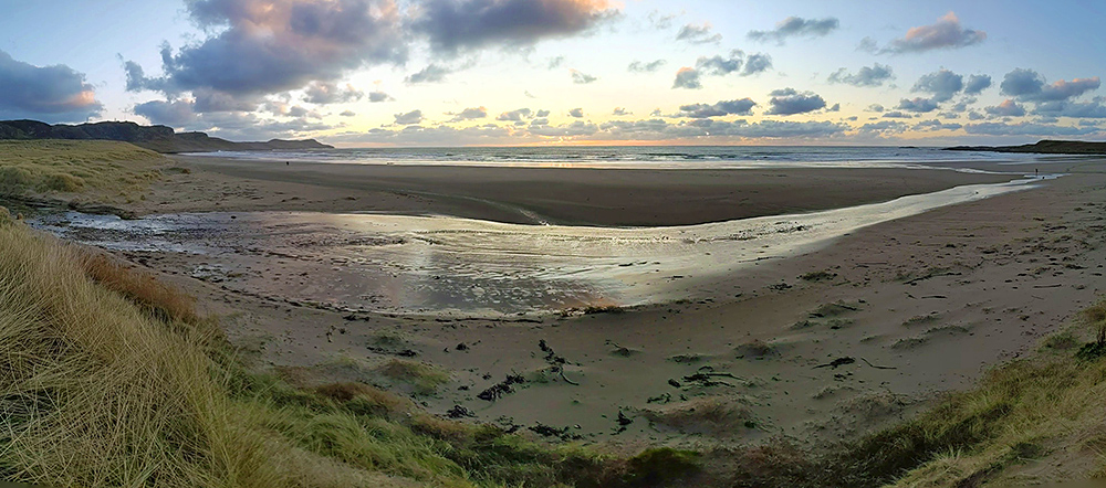 Panoramic picture of a sunset over a bay with a beach in November