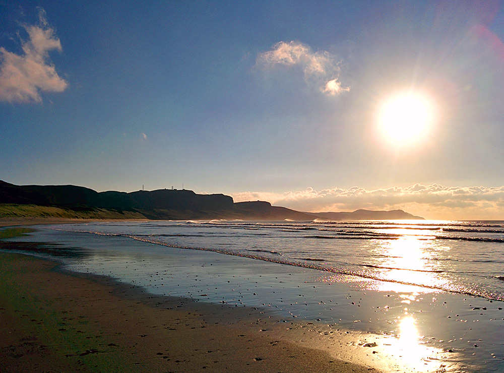Picture of a low golden winter sun over a bay with a sandy beach