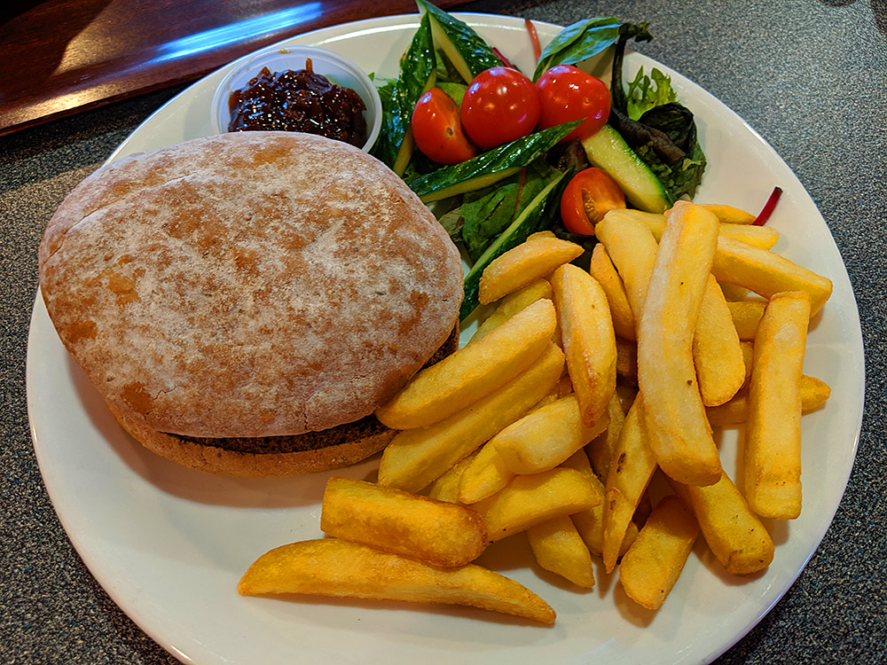 Picture of a burger in a bap with some chips