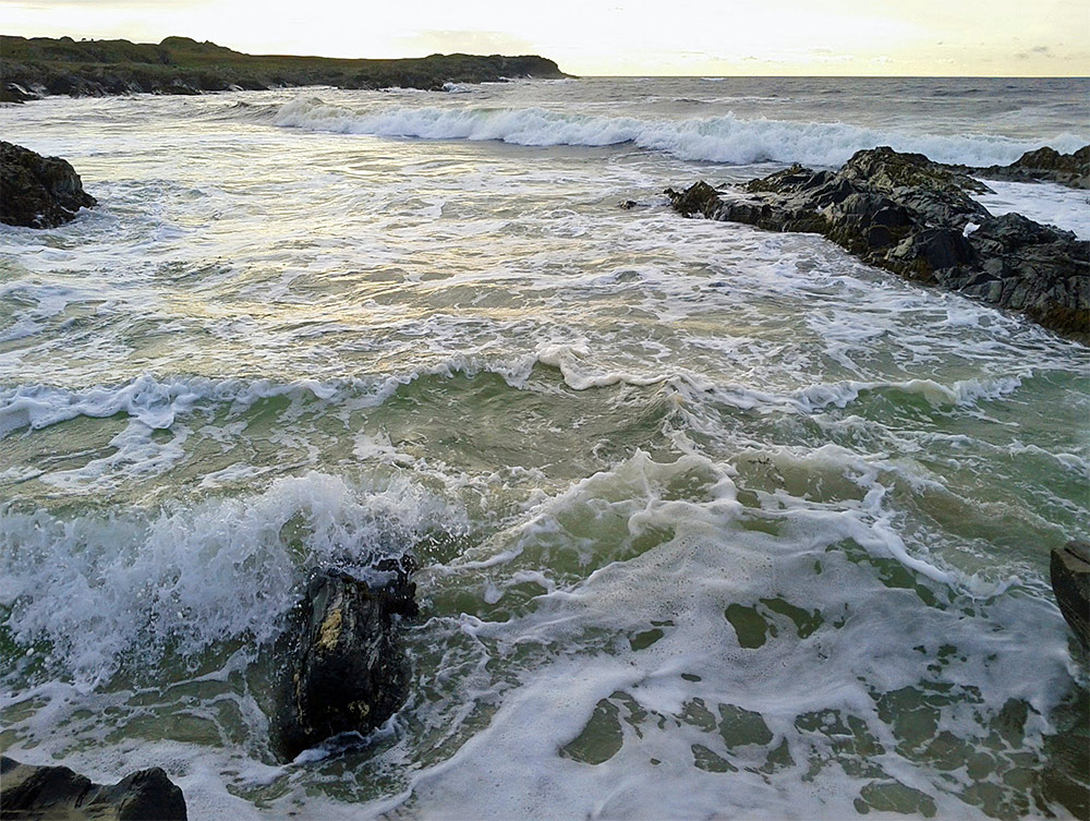 Picture of waves rushing over a beach with some rocks