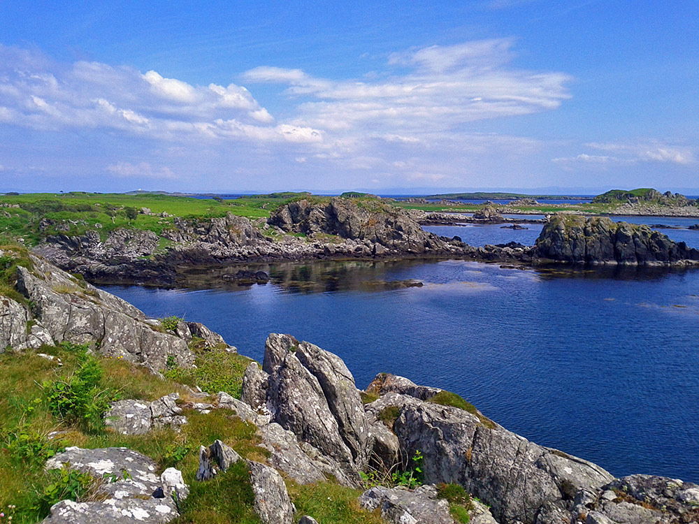 Picture of a rugged coastline with cliffs, inlets, rocks and grassy hills