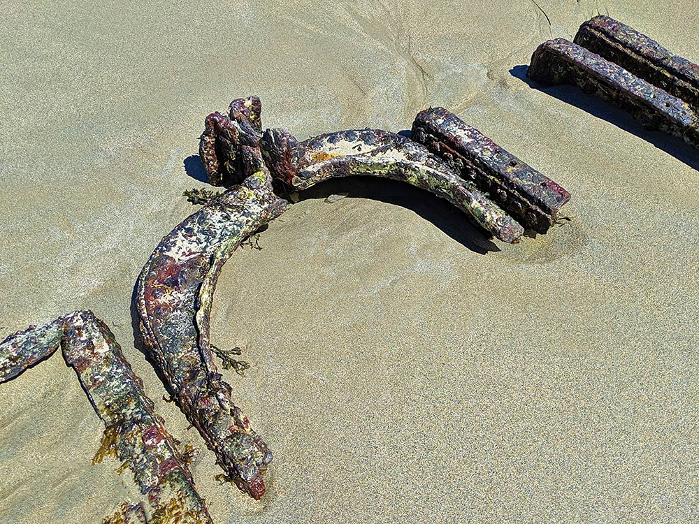Picture of the rusty remains of a ship wreck in the sand of a beach