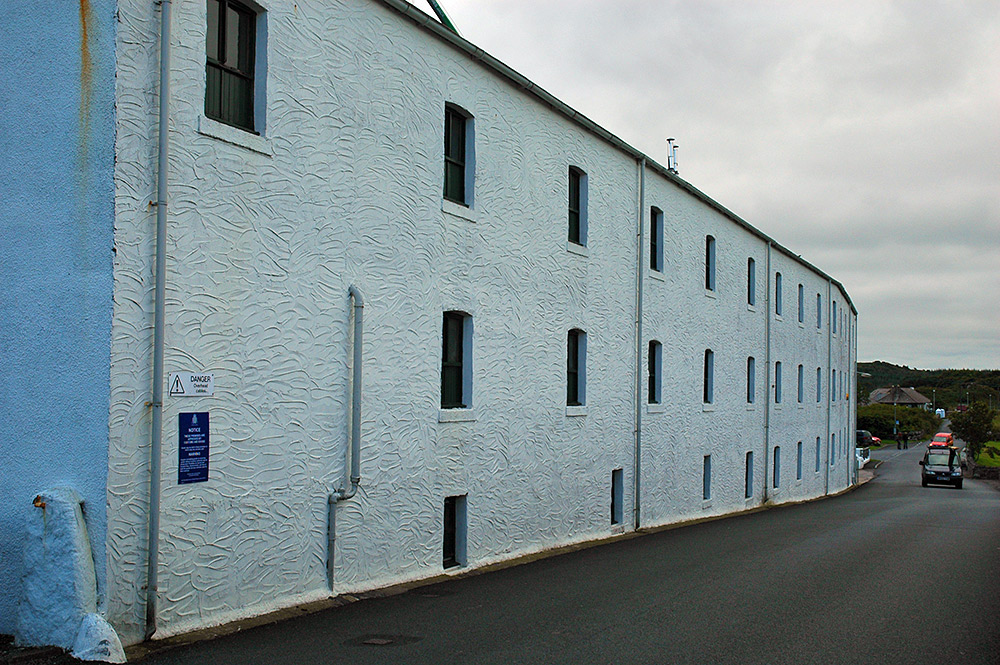 Picture of whitewashed distillery (Lagavulin) from a road past it