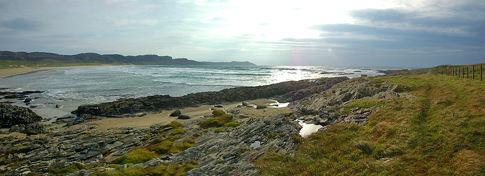 Panoramic picture of a wide bay with a beach and crags in the distance