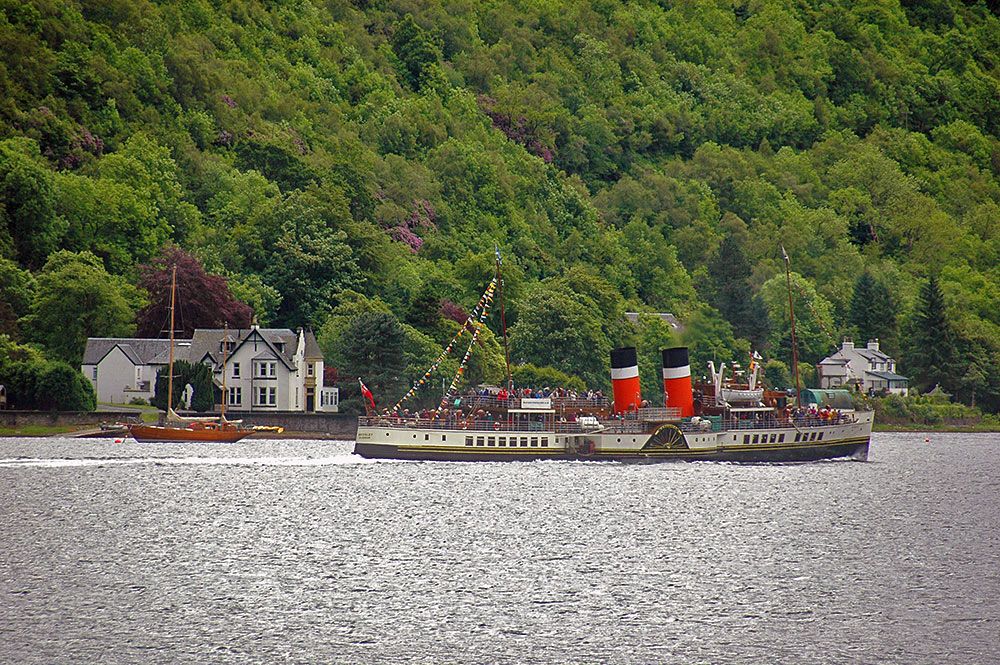 Picture of the paddle steamer Waverley cruising on a loch, a wooden old sailing yacht anchored in the background