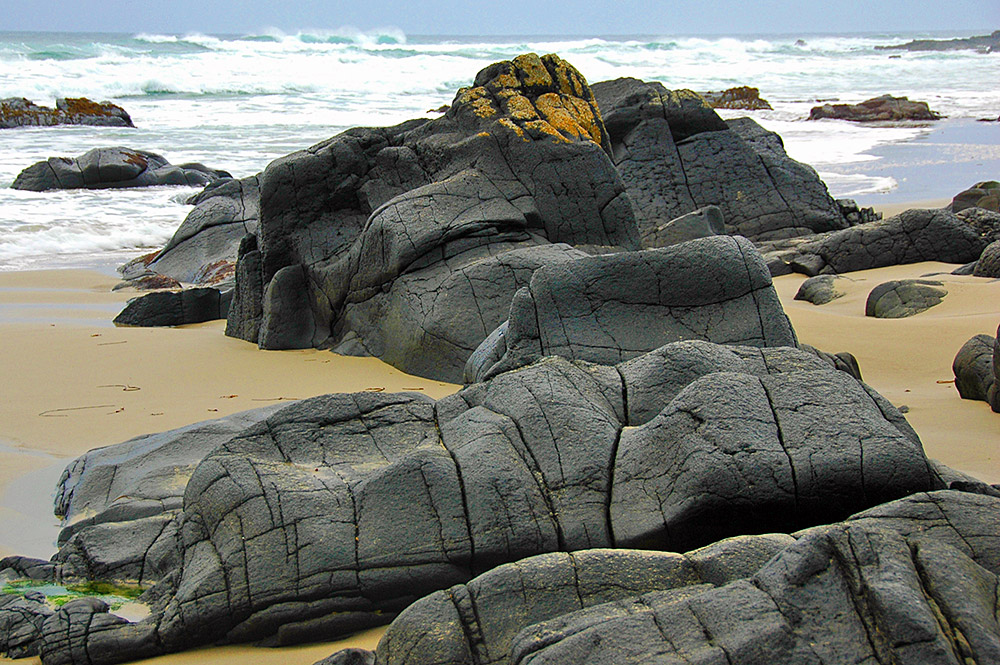 Picture of some weathered smooth rocks on a beach on a cloudy day