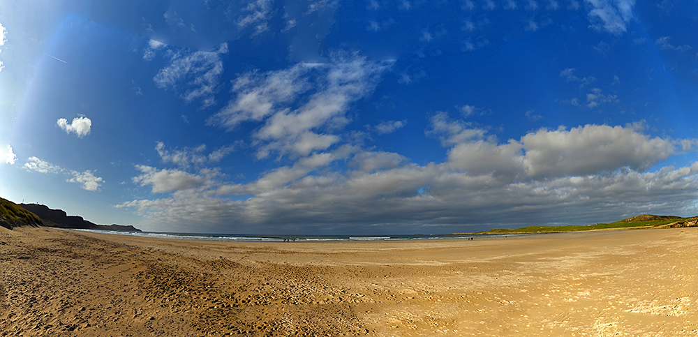 Panoramic picture of a wide sandy beach with some threatening clouds on the horizon
