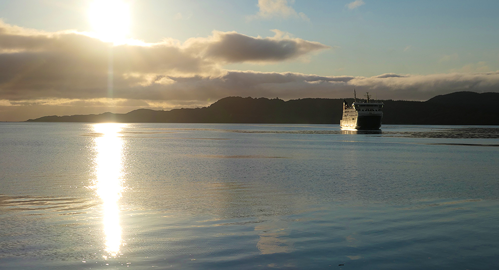 Picture of a ferry arriving in a sea loch under a low evening sun