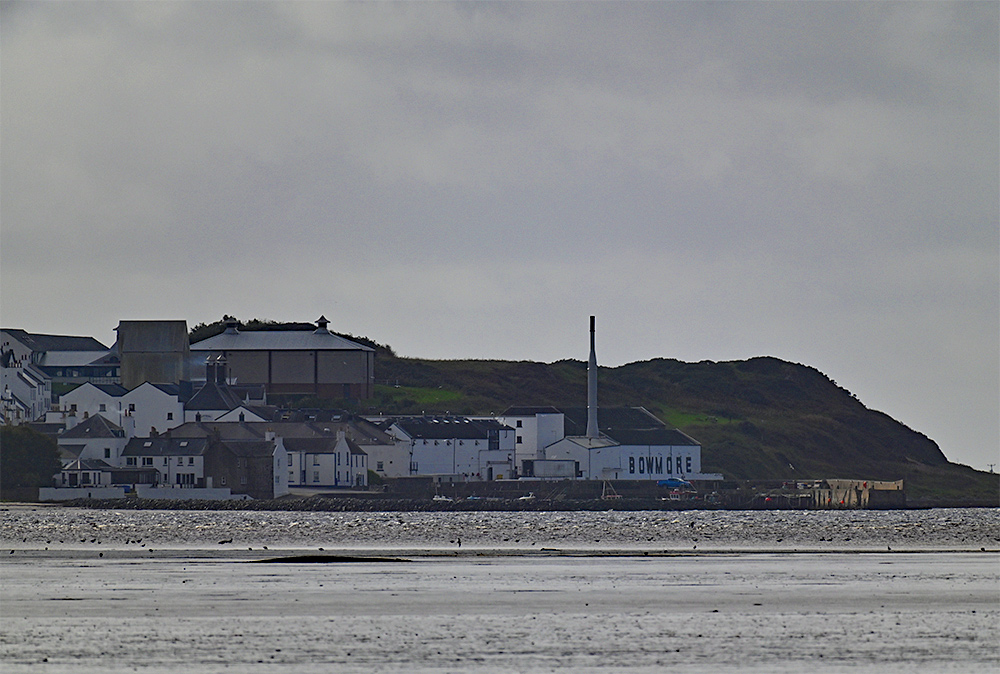 Picture of a small village harbour and a coastal distillery seen across a sea loch