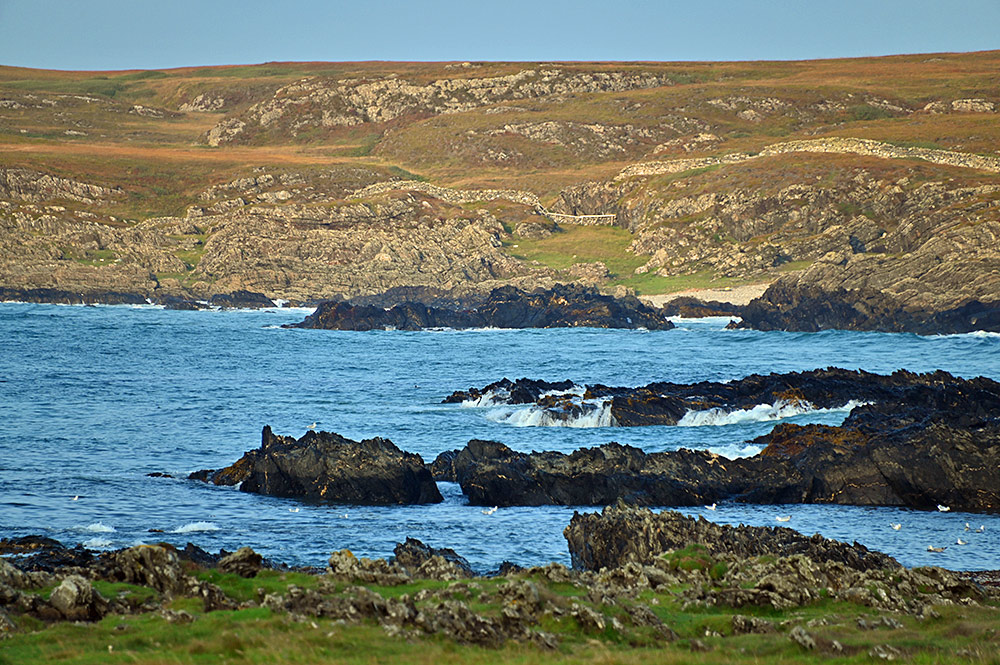 Picture of a rocky coastline with a pebble beach in the distance