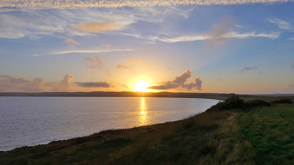 Picture of a sunset seen across a sea loch from a small hill on the side of the loch